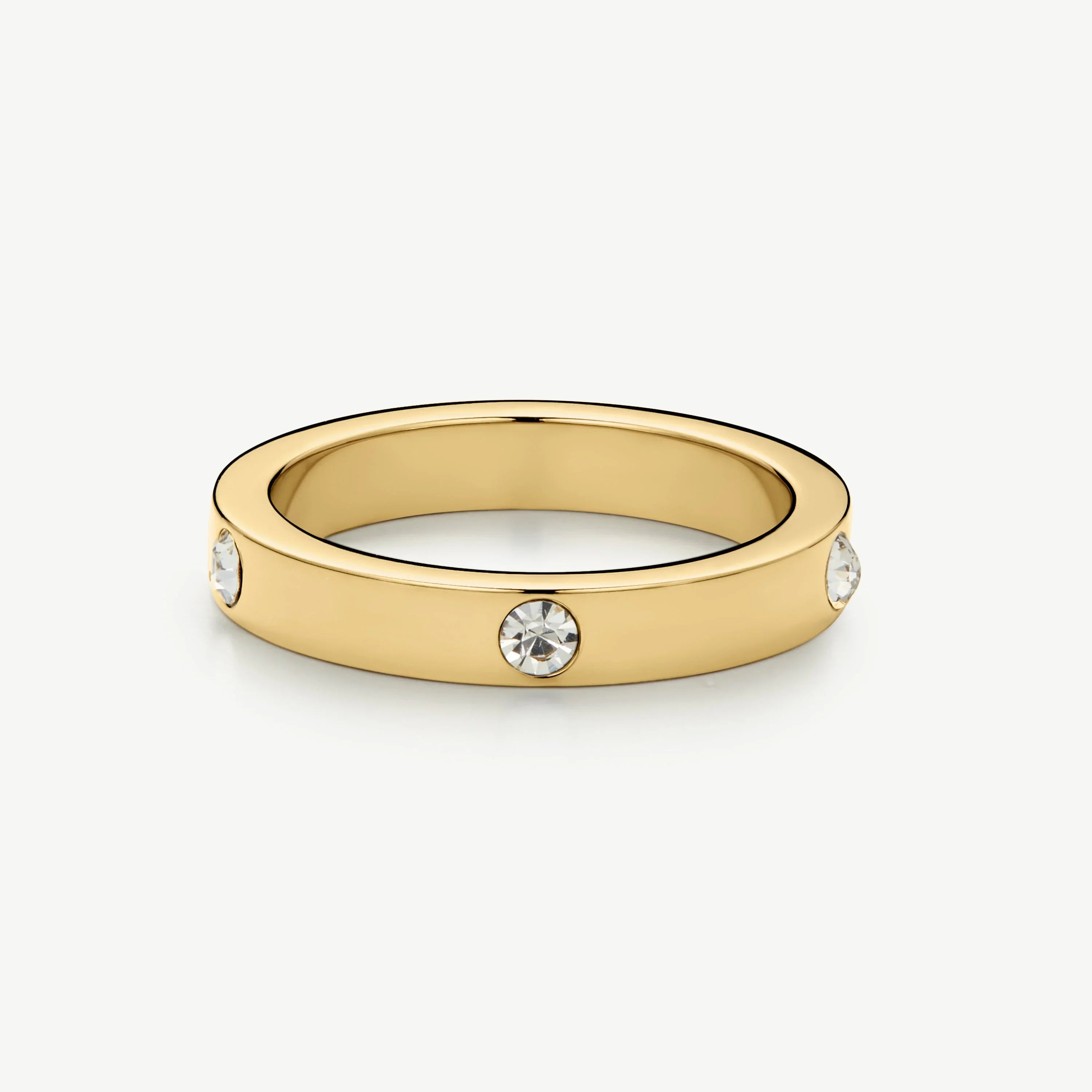 Gold ring with three embedded round clear gemstones on a white background