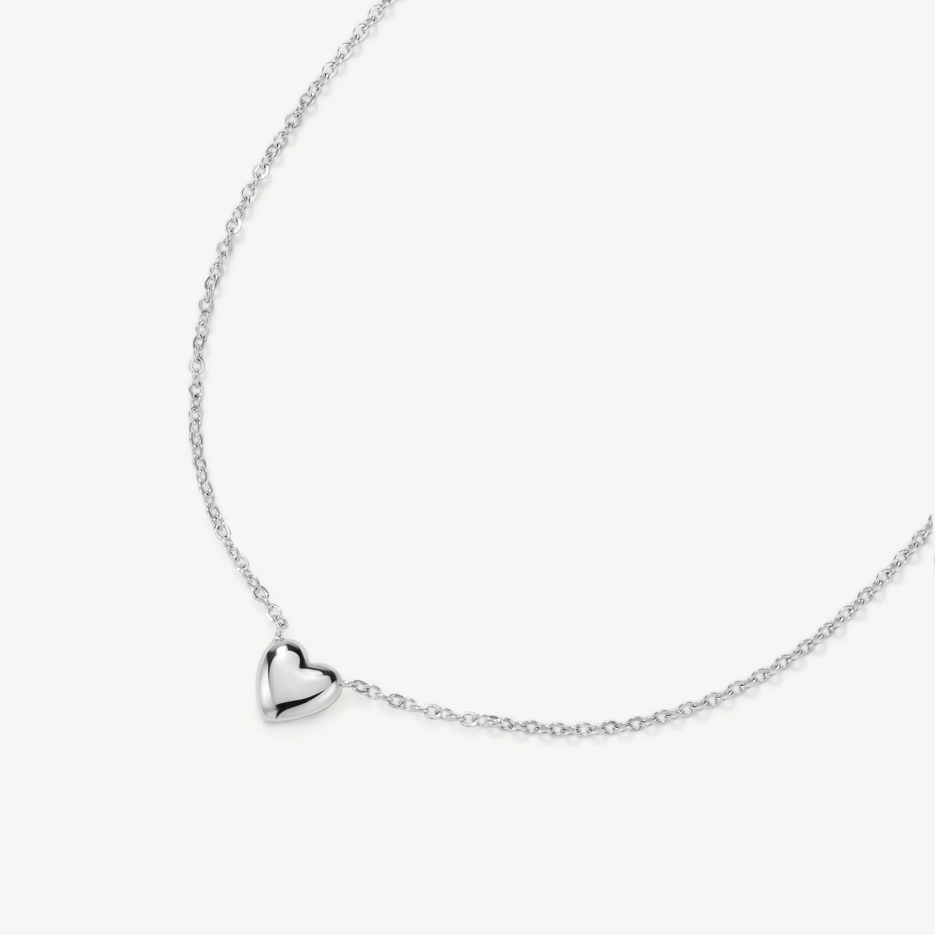 Silver necklace with small heart pendant on delicate chain against white background