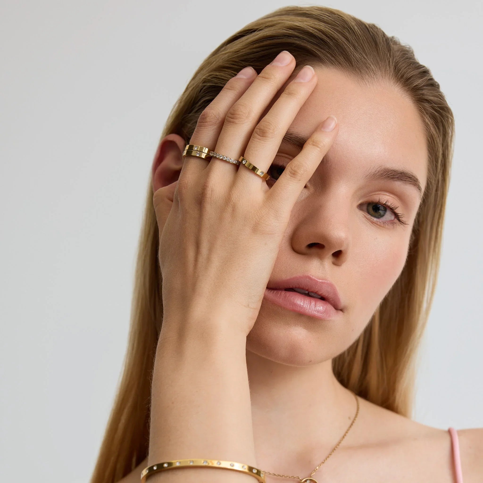 Woman wearing gold stacking rings and matching bracelet with diamond accents close-up