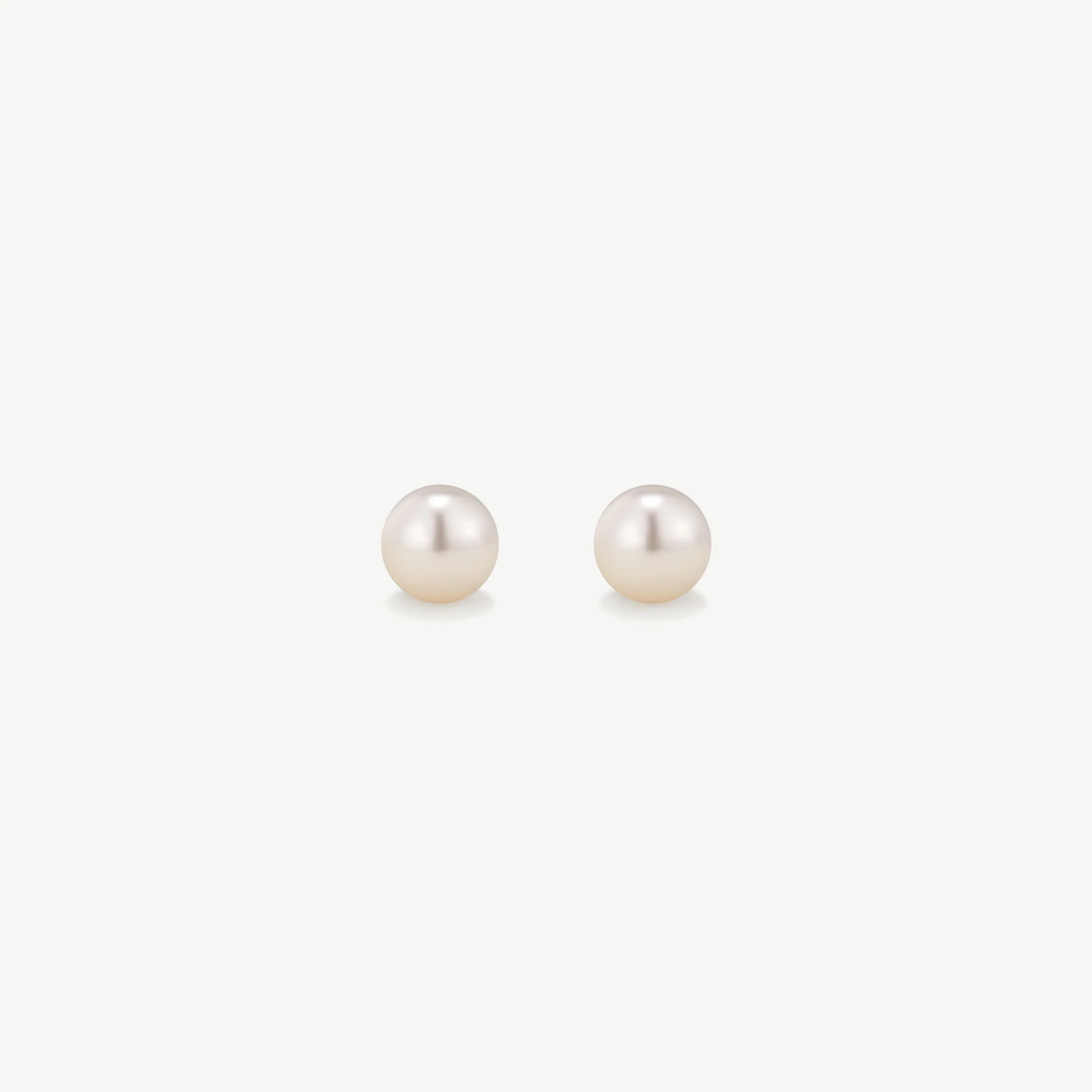 Pair of classic white pearl stud earrings on a white background