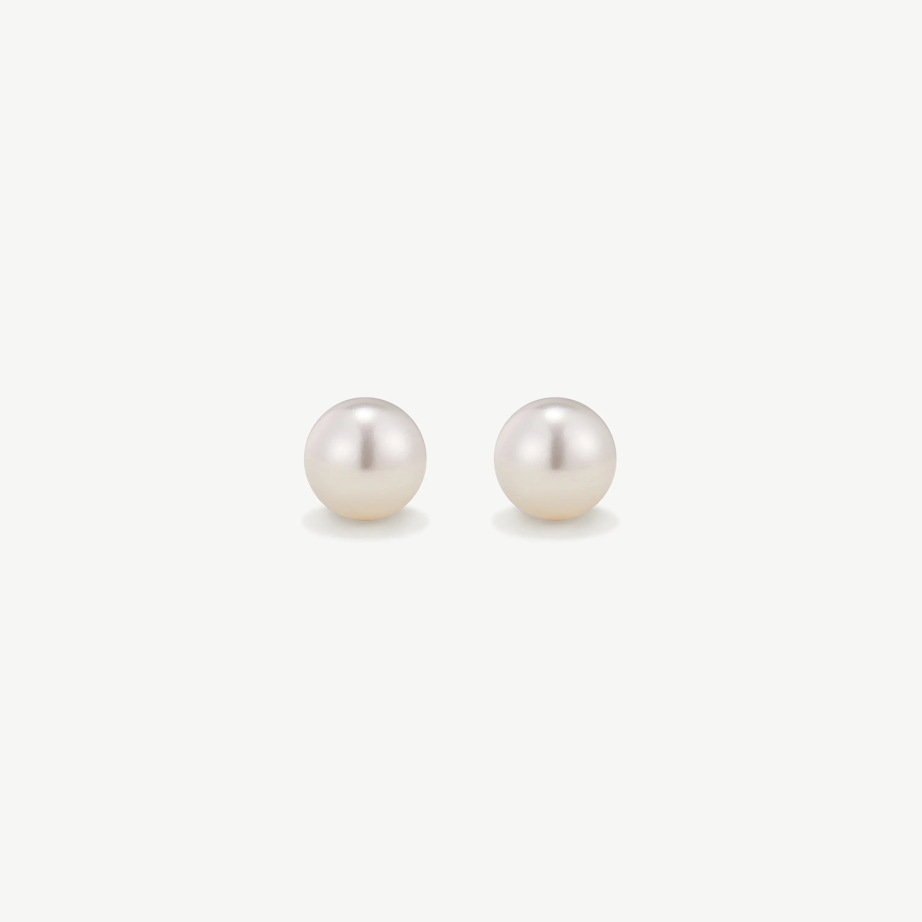 Pair of elegant white pearl stud earrings on a plain white background