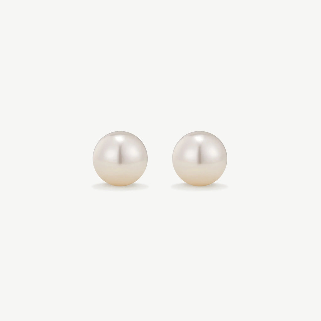 Pair of classic round white pearl stud earrings on white background