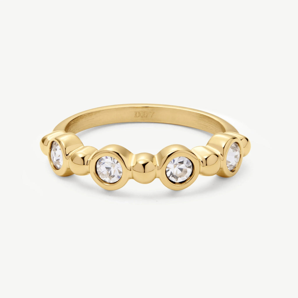 Elegant gold ring with five bezel-set round white gemstones on white background
