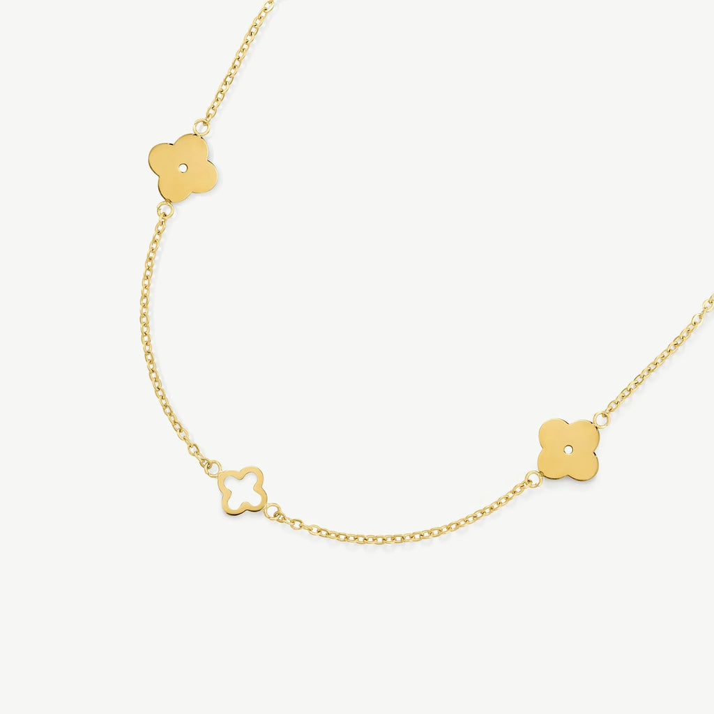Delicate gold chain necklace with clover-shaped pendants on white background