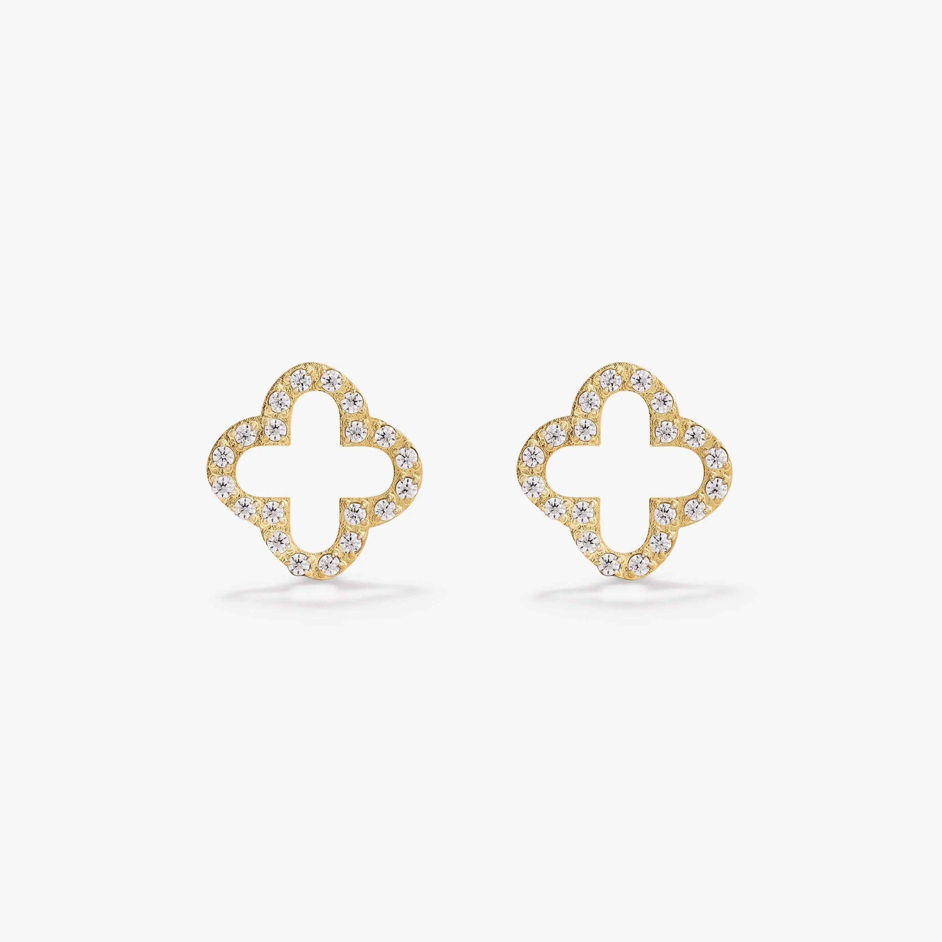 Gold stud earrings shaped like clover with clear rhinestones on white background
