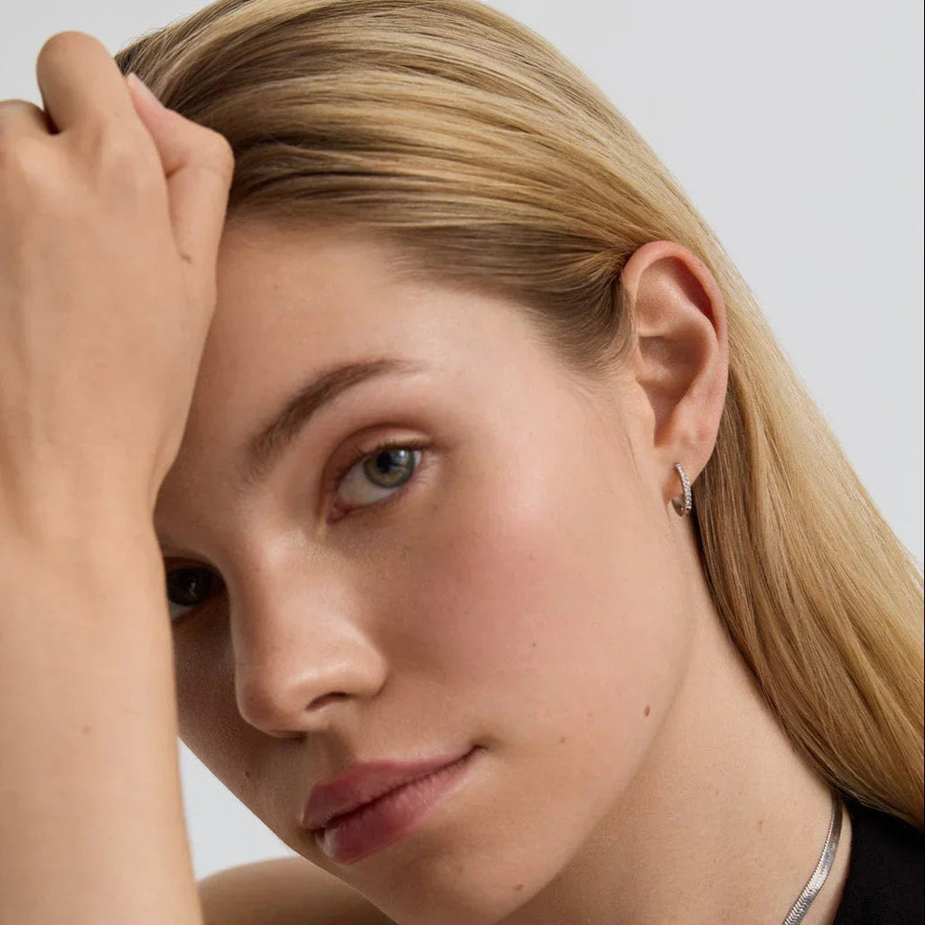Close-up of woman with blonde hair wearing silver hoop earrings and a silver chain necklace