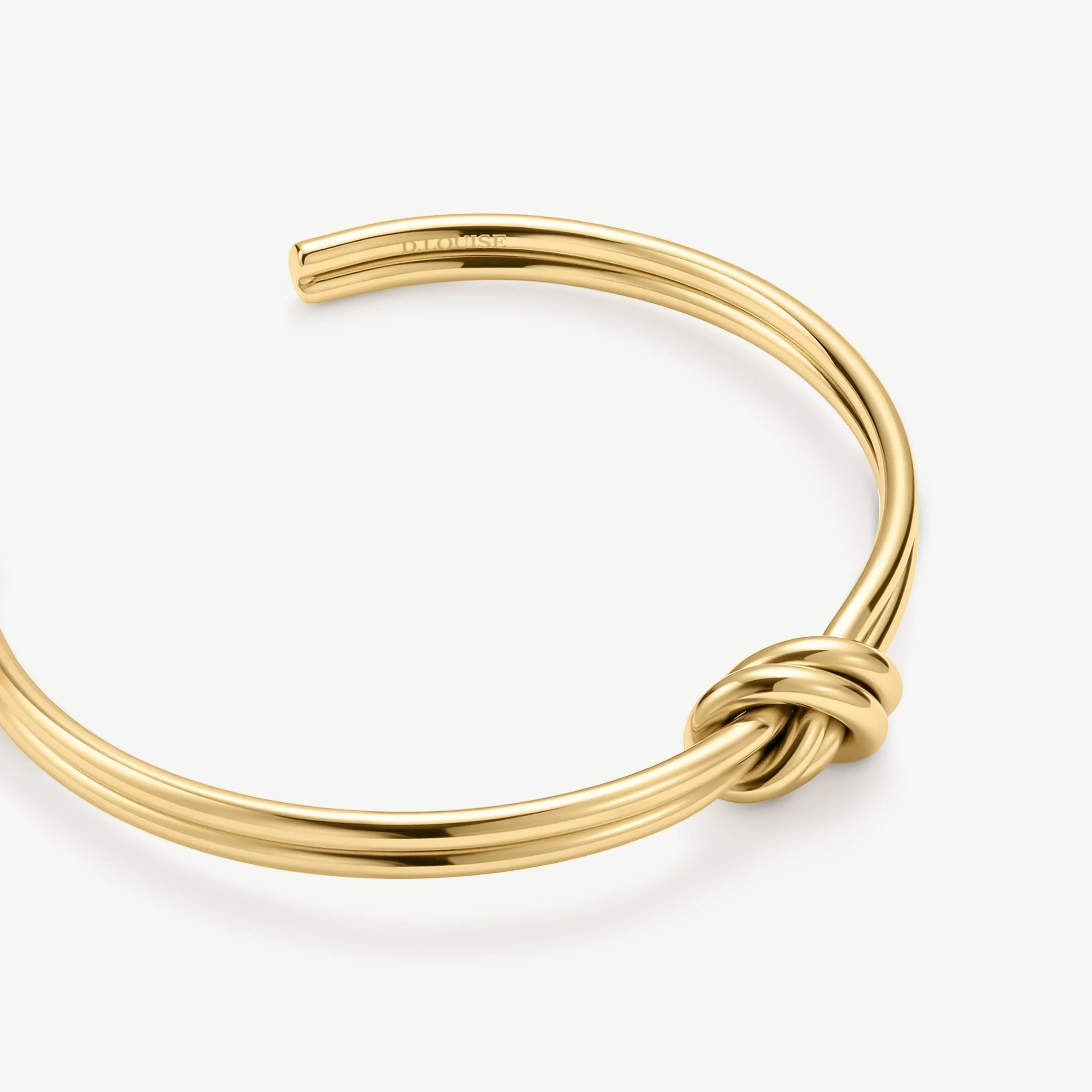 Elegant gold cuff bracelet with a distinctive knot design on a white background