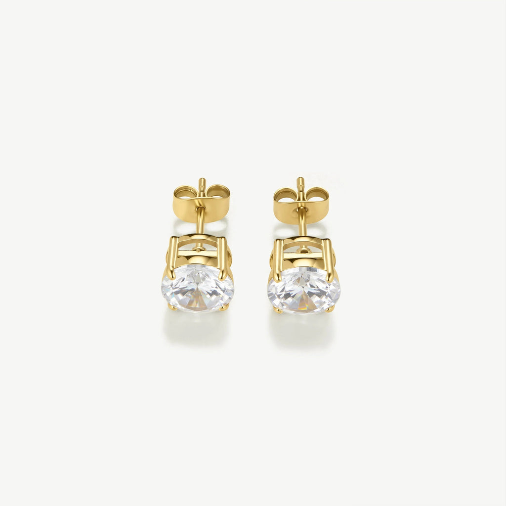 Pair of gold stud earrings with round clear gemstones on white background