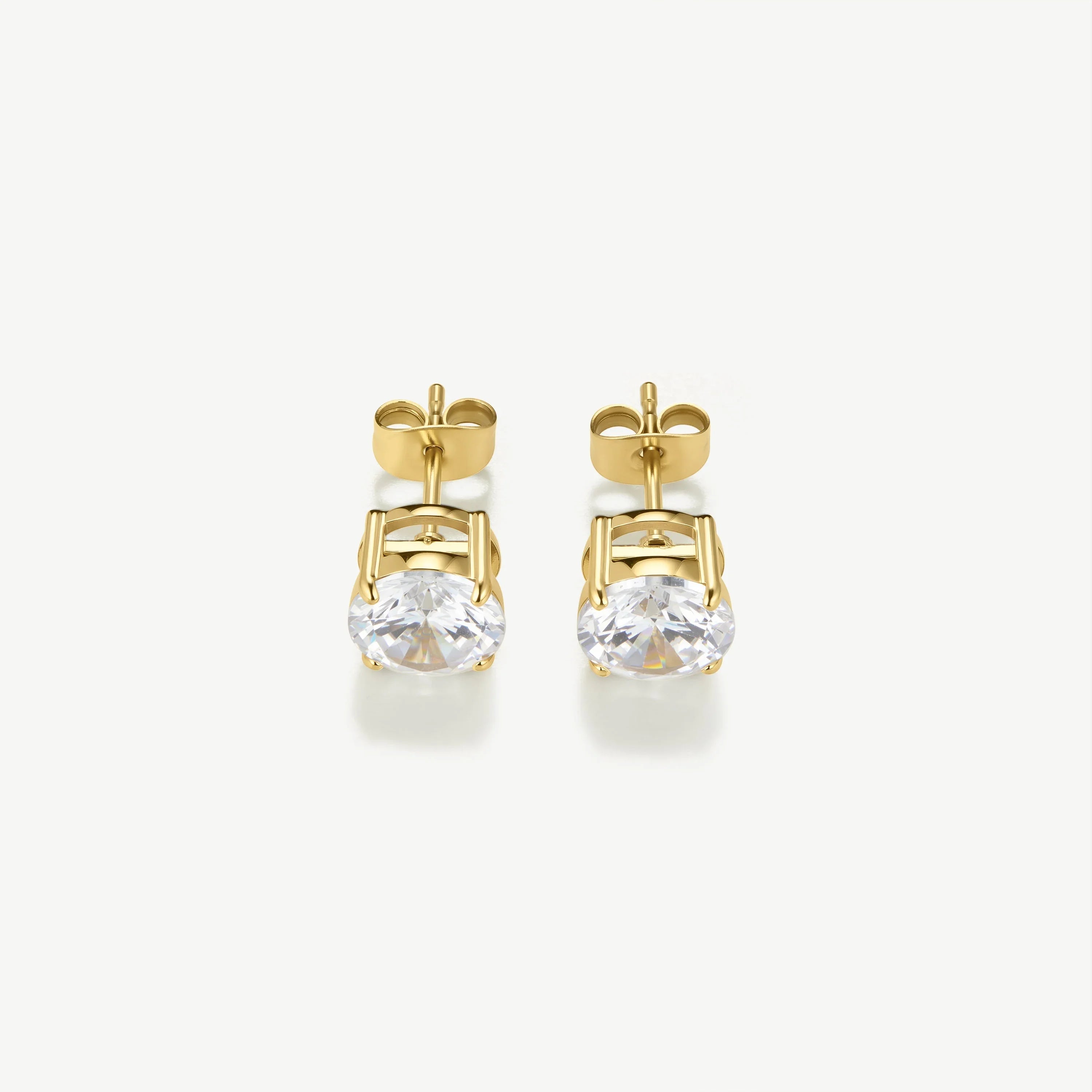 Pair of gold stud earrings with round clear gemstones on white background