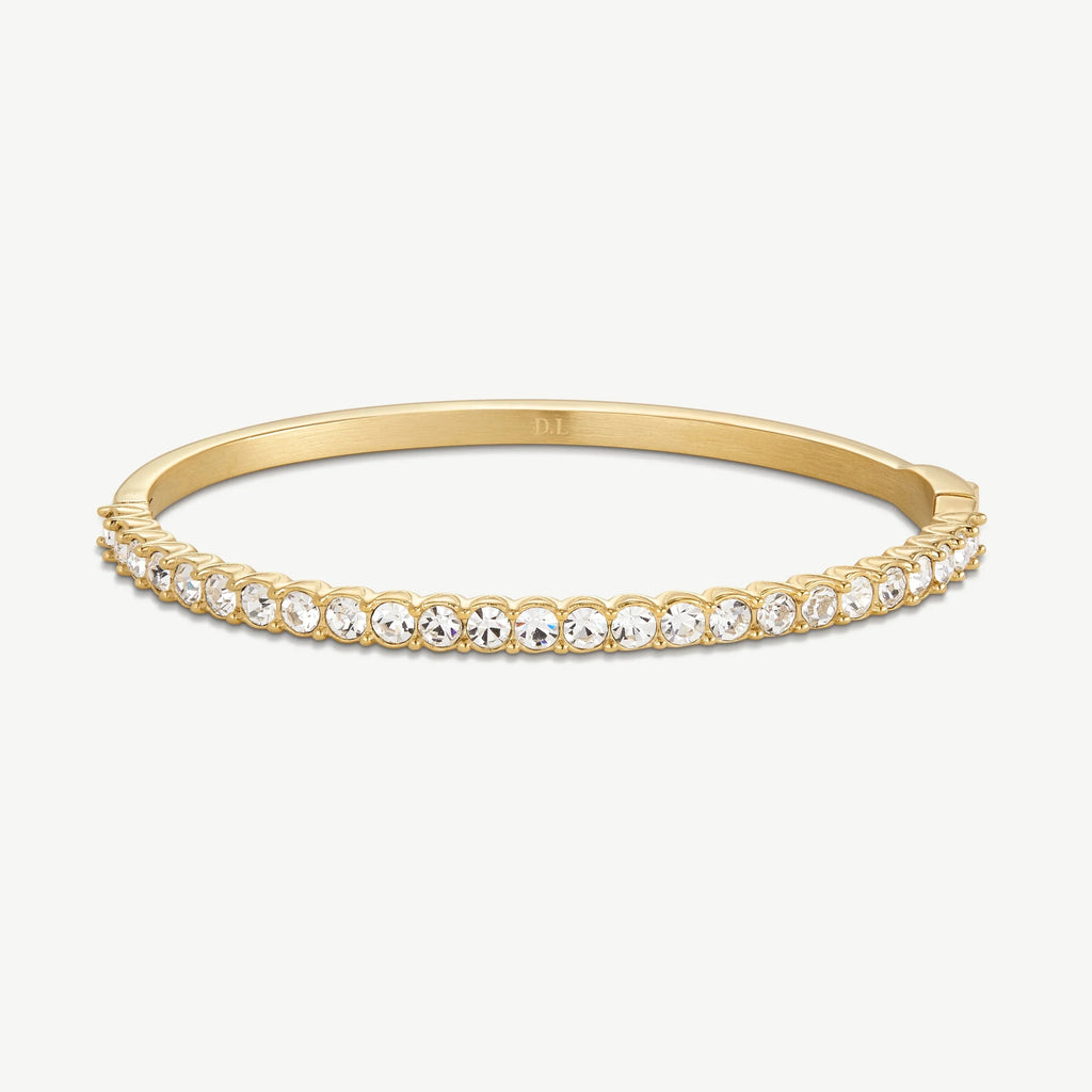 Gold bangle bracelet with round clear crystals in a single row on a white background