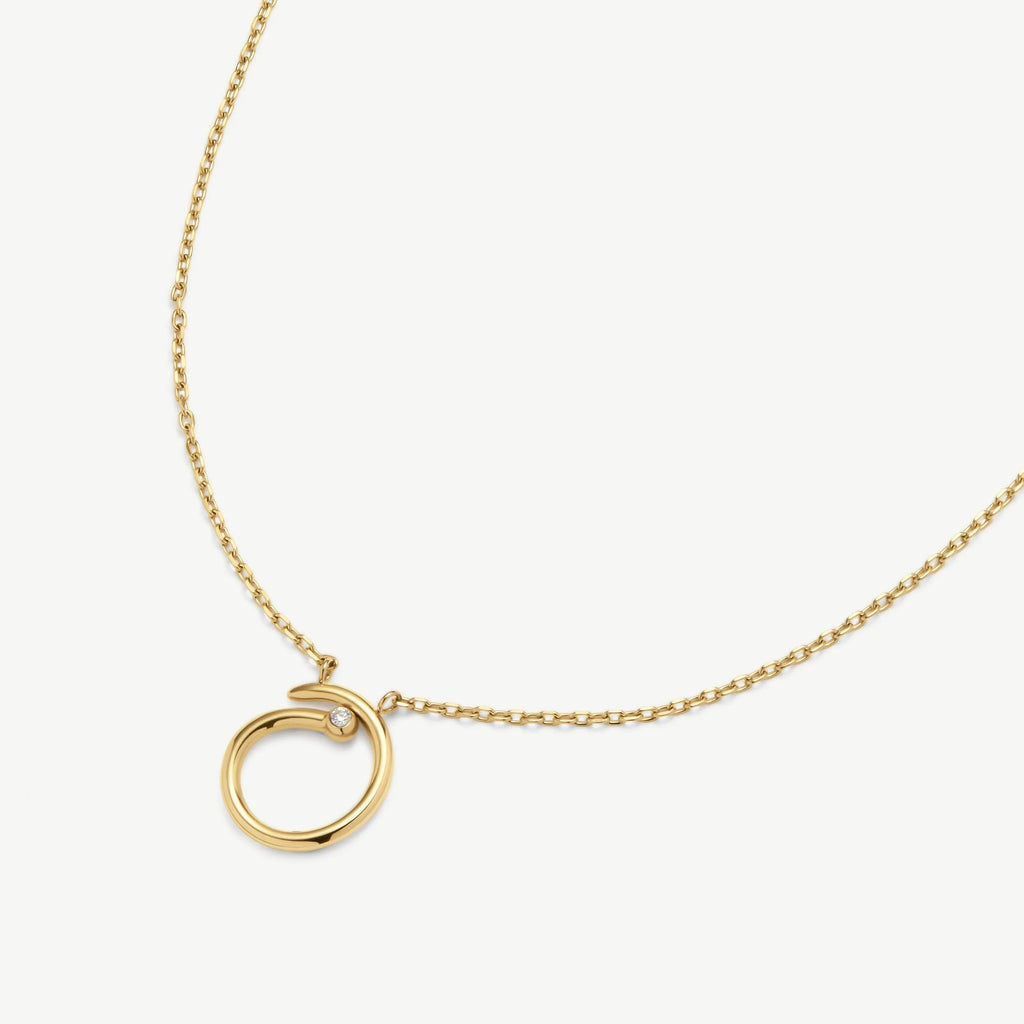 Gold necklace with circular pendant featuring a small diamond accent on white background